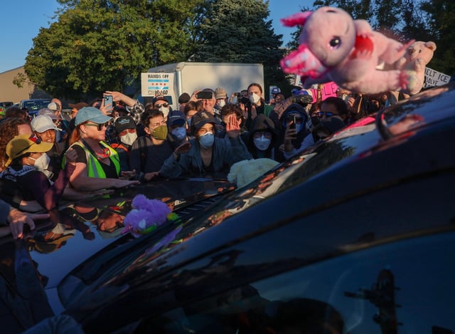 Protesters surround the SUV of a federal agent and try and prevent him from driving down Harvard Street to the US Immigration & Customs Enforcement facility on Sept. 26, 2025, in Broadview.  Protesters and federal agents faced off throughout the morning. Federal agents used several kinds of chemical gasses, baton rounds, and arrested at least two people while protesters refused to clear the street. (Stacey Wescott/Chicago Tribune)