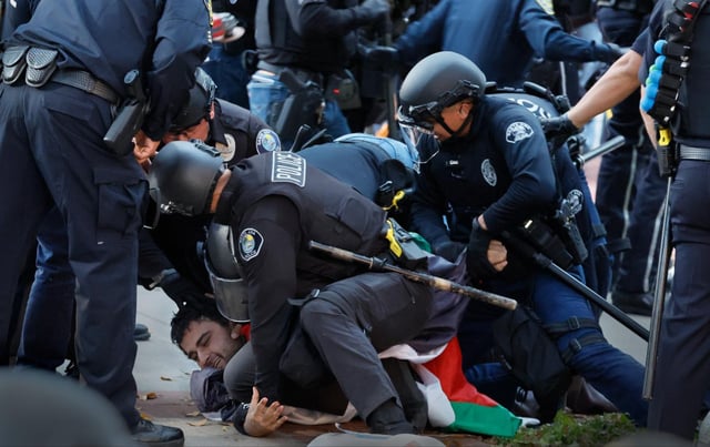 A pro-Palesitine demonstrator who ended up with a bloody nose is taken into custody by police as they break up the pro-Palestine encampment at UC Irvine on Wednesday, May 15, 2024.