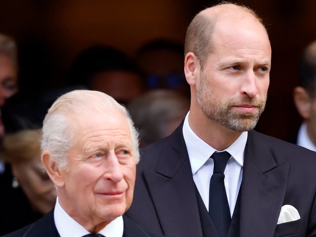 Prince William and King Charles wearing suits and ties standing next to each other