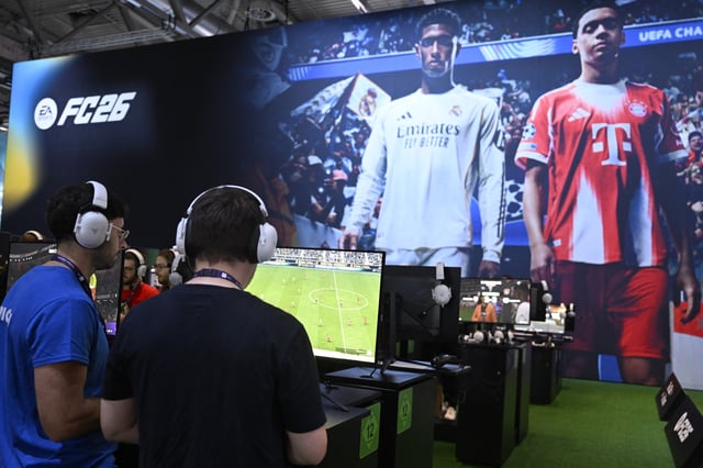 Gamers play the video game "EA Sports FC 26 in front of a screen featuring English midfielder Jude Bellingham (L) and Bayern Munich's German midfielder Jamal Musiala during the Gamescom video games trade fair at the Trade Fair Center in Cologne, western Germany, on the first day of the fair on August 20, 2025. The 2025 edition of the vast Gamescom trade fair in Cologne, Germany, had its opening night on August 19, 2025 and will be running from August 20 to 24, 2025. (Photo by Ina FASSBENDER / AFP) (Photo by INA FASSBENDER/AFP via Getty Images)