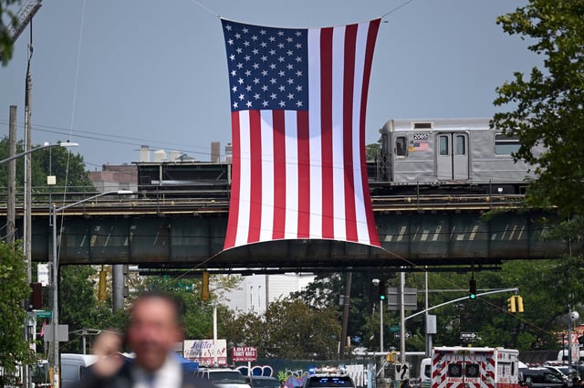 A large U.S. flag hangs over White Plaines Rd, where funeral services for slain New York City Police Officer Didarul Islam are to be held, in the Bronx borough of New York City, NY. July 31, 2025. Officer Islam was killed while on private security duty at the Blackstone Headquarters on Park Avenue on Monday July 28 , along with three other victims, Julia Hyman, Aland Etienne and Wesley LePatner, after an armed man entered the billing with an assault riffle. (Photo by Anthony Behar/Sipa USA)(Sipa via AP Images)