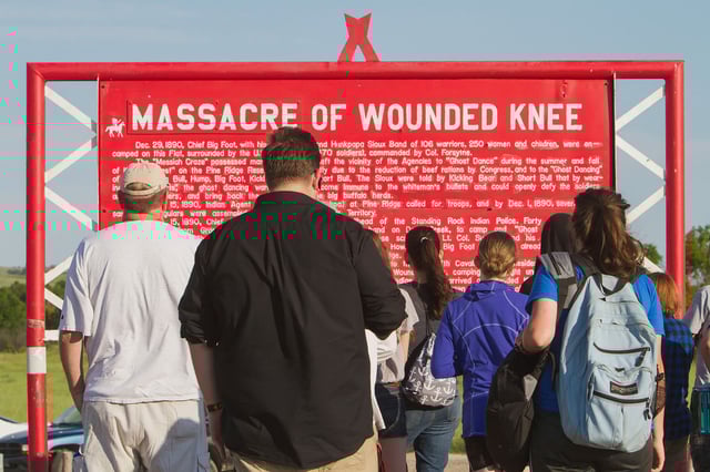 Visitors read a plaque at the Wounded Knee Massacre memorial, which marks the site of the December 29, 1890 killing of Lakota men, women, and children near Wounded Knee Creek on the Pine Ridge Indian Reservation, South Dakota.