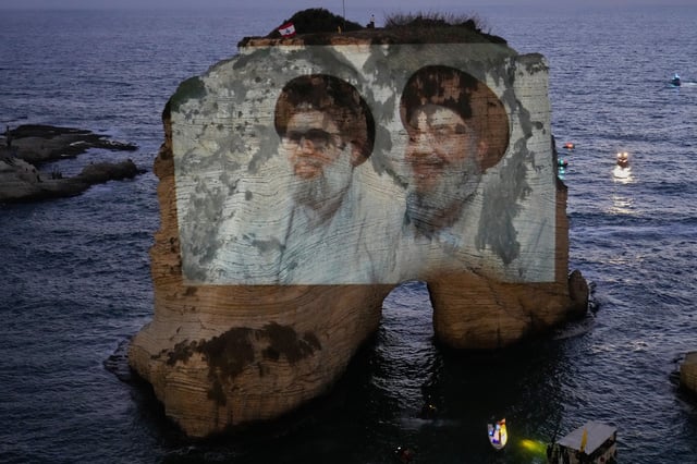 Portraits of former Hezbollah leaders Sayyed Hassan Nasrallah, right, and Hashem Safieddine, are projected onto the landmark Raouche sea rock during an event commemorating the anniversary of their assassination, in Beirut, Lebanon, Thursday, Sept. 25, 2025. (AP Photo/Hussein Malla)