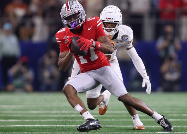 Ohio State wide receiver Carnell Tate (17) makes a catch against Texas defensive back Malik Muhammad (5) during the College Football Playoff semifinal in the Cotton Bowl at AT&T Stadium.