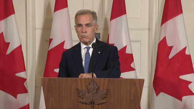 Prime Minister Mark Carney reacts to a reporter's question during a news conference in London.
