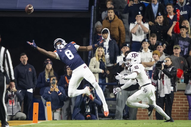 Wide receiver Cam Coleman #8 of the Auburn Tigers attempts to catch a pass in front of defensive back Dezz Ricks #10 of the Texas A&M Aggies at Jordan-Hare Stadium on November 23, 2024 in Auburn, Alabama.