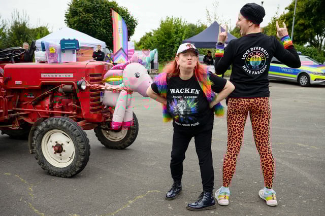 Die beiden Organisatorinnen Pride Sis (l.) und Eve Champagne stehen vor Beginn der Demonstration zum ersten Christopher Street Day (CSD) in der Gemeinde Wacken neben einem roten Traktor.