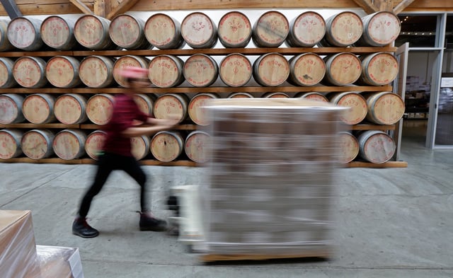 In this Nov. 14, 2017 photo, Nathan Bazan moves a pallet of supplies past whiskey aging in oak barrels at the Westland Distillery in Seattle. Westland is taking an unusual step for America's booming spirits industry: making a whiskey using smoke from peat grown locally in Washington state. (AP Photo/Ted S. Warren)