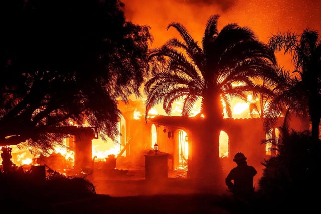 FILE – A firefighter watches as flames from the Mountain Fire consume a home in Camarillo, Calif., Nov. 6, 2024. (AP Photo/Noah Berger, File)