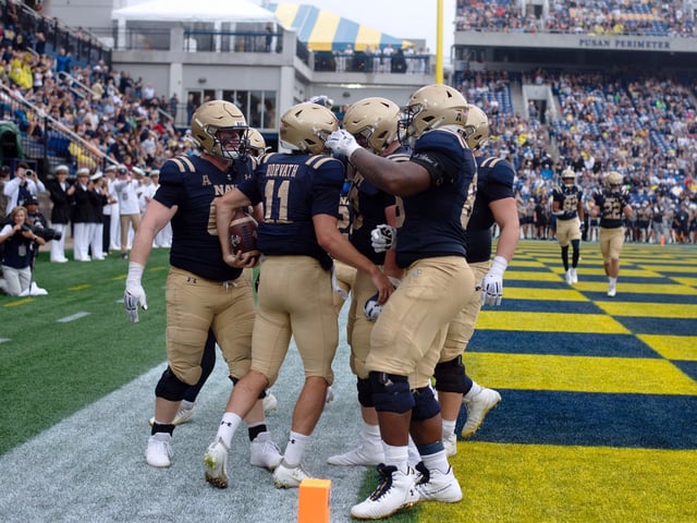 Sept. 27, 2025- Navy players gather around quarterback Blake Horvath to celebrate Horvath's second quarter touchdown against Rice at Navy-Marine Corps Stadium in Annapolis.(John Gillis/Freelance)