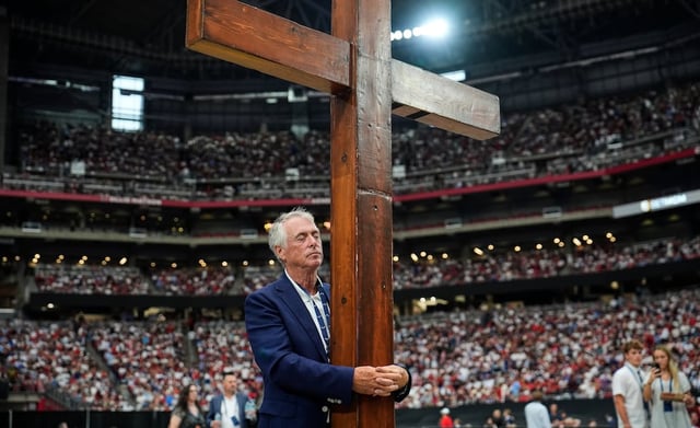 Dan Beazley stands with a cross at a memorial for conservative activist Charlie Kirk, Sunday, Sept. 21, 2025, at State Farm Stadium in Glendale, Ariz.