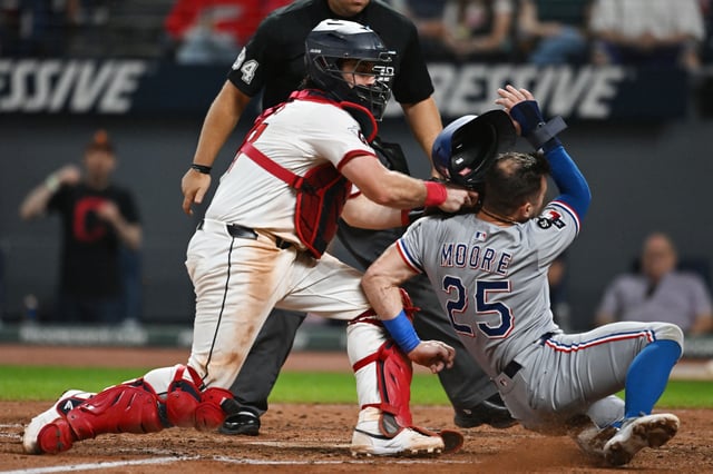 Sep 27, 2025; Cleveland, Ohio, USA; Cleveland Guardians catcher Austin Hedges (27) tags out Texas Rangers right fielder Dylan Moore (25) during the eighth inning at Progressive Field. Mandatory Credit: Ken Blaze-Imagn Images