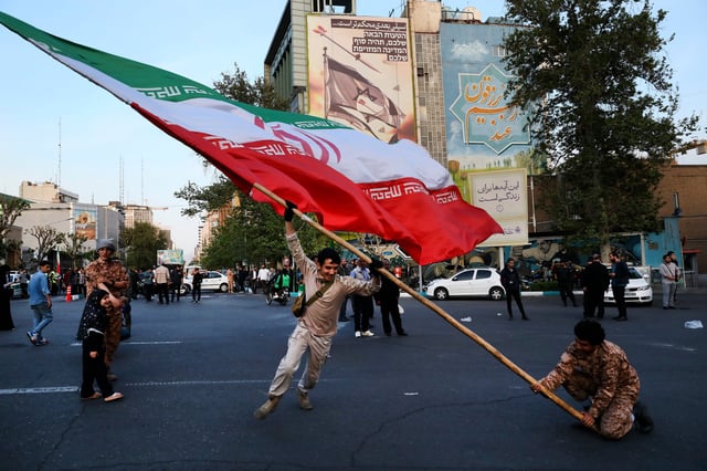 Manifestantes ondean una enorme bandera iraní en su reunión antiisraelí frente a la plaza Felestin (Palestina), en Teherán, Irán, el lunes 15 de abril de 2024. (Foto AP/Vahid Salemi)