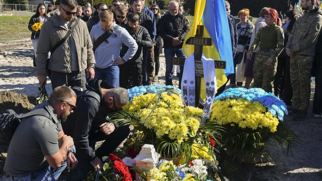 Varias personas asisten al funeral de tres soldados ucranianos, este sábado en Leópolis.