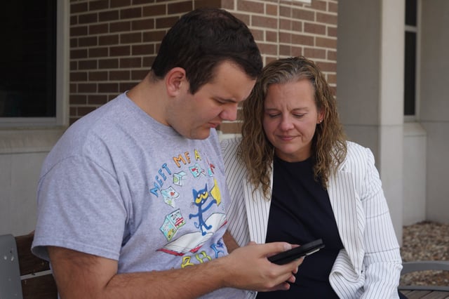 Rachel Deaton, director of training and legislation at the Autism Society of Indiana, sits with her 22-year-old autistic son, Luke, outside a public library in a northeastern suburb of Indianapolis, on Tuesday, Sept. 23, 2025. (AP Photo/Obed Lamy)