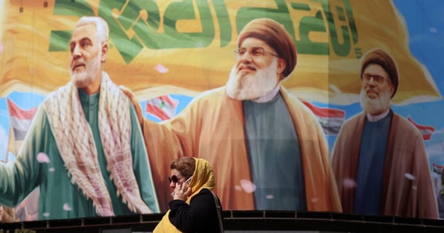 An Iranian woman walks past a billboard in Tehran on Saturday. Embargoes, asset freezes and other punitive measures threaten to damage Iran’s already fragile economy. EPA