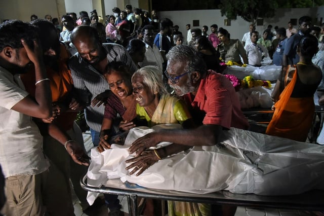 Des proches éplorés entourent le corps d'une victime tuée dans une bousculade la veille au soir lors d'un rassemblement de campagne de l'homme politique et ancien acteur Vajay, dans l'État du Tamil Nadu, le 28 septembre 2025 en Inde