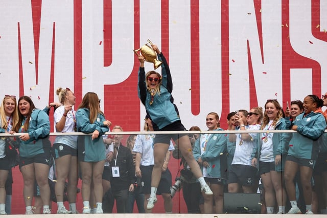 Zoe Aldcroft holds the trophy as England players celebrate at a Red Roses Champions Party (Photo: Henry Nicholls/AFP)