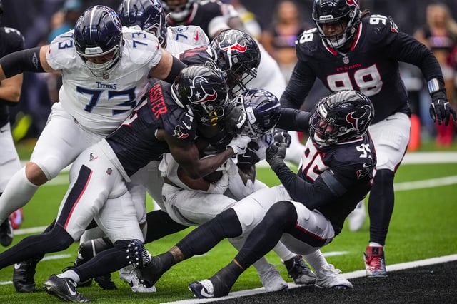 Tennessee Titans running back Tony Pollard is stuffed at the line of scrimmage by Houston Texans cornerback Kamari Lassiter (4) and defensive end Derek Barnett (95) during the second half of an NFL football game at NRG Stadium in Houston, Sunday, Sept. 28, 2025.
