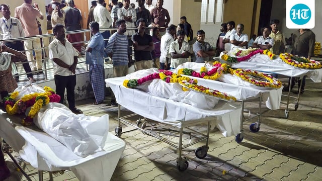 People stand near mortal remains of victims, who died after a stampede broke out at actor and TVK chief Vijay's rally on Saturday, at the government hospital, in Karur.
