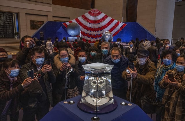 Spectators in Beijing gather around a case holding lunar rock and debris collected by a mission of China's space program, seen here on display in 2021.