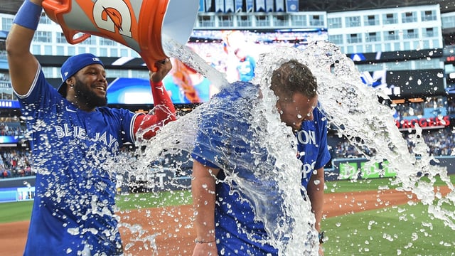 Sep 28, 2025; Toronto, Ontario, CAN; Toronto Blue Jays first baseman Vladimir Guerrero Jr. (27) douses manager John Schneider (14) with ice water as they celebrate winning the American League East Division with a win over the Tampa Bay Rays at Rogers Centre. Mandatory Credit: Dan Hamilton-Imagn Images