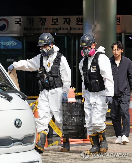 Police investigators carry burnt lithium-ion batteries as they examine a fire at the National Information Resources Service in the central city of Daejeon on Sept. 29, 2025, to determine the cause of the fire that occurred at the center on Sept. 26. (Yonhap)
