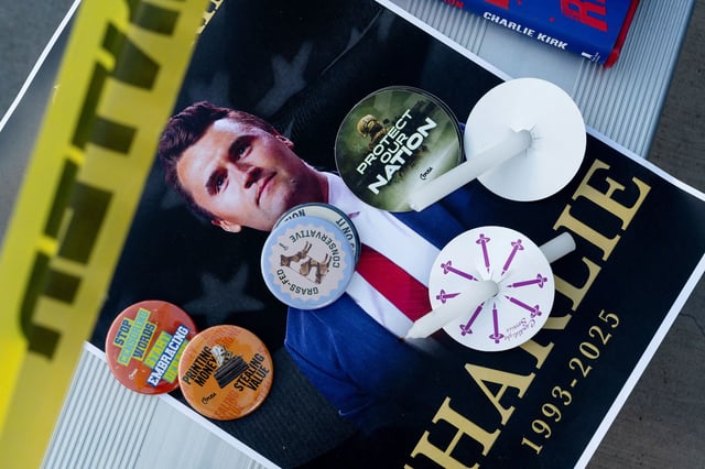 Pins and candles are placed on a poster with an image of slain conservative activist Charlie Kirk as Turning Point USA hosts a vigil for him at Colorado State University, on what was supposed be the next stop on his speaking tour, in Fort Collins, Colorado, on September 18.