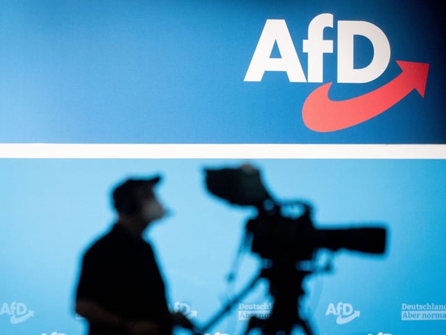 Eine Fernsehkamera steht vor einer Wand mit dem AfD-Logo.