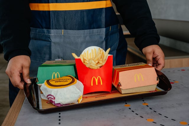 An employee carries a tray of food, including french fries and hamburgers, to a customer at a McDonald's restaurant in Zion, Illinois, on February 19, 2025.