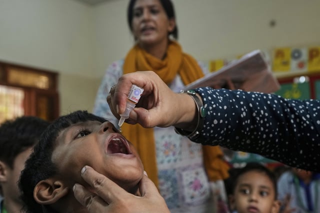 A health worker administers a polio vaccine to a child in a school, in Karachi, Pakistan, Monday, Sept. 1, 2025. (AP Photo/Fareed Khan)