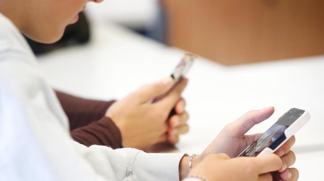 Jugendliche halten Smartphones in den Händen. 