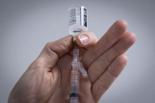 A pharmacist draws out influenza vaccine from a vial at a pharmacy in Kingston, Ontario on Tuesday, October 20, 2020. THE CANADIAN PRESS IMAGES/Lars Hagberg
