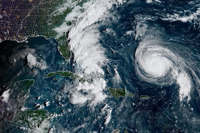 In this weather satellite photo taken around 7:40 a.m. Sunday, Hurricane Humberto, at right, appears as a tight, compact spiral of clouds in the western Atlantic, north of Puerto Rico. A tropical depression, which later became Tropical Storm Imelda, had formed near the Bahamas and is visible as band of thick clouds to the left or west of Humberto.
