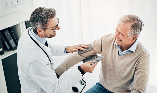 File photo: a doctor attends to an older male patient in hospital.