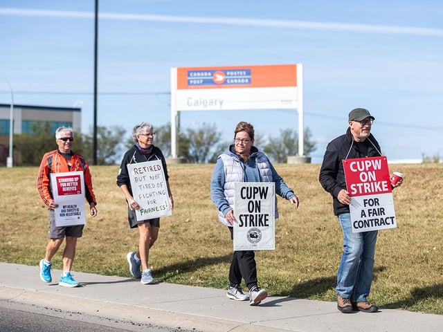 Postal workers picket in front of the Canada Post plant in Calgary on Sunday, Sept. 28, 2025.