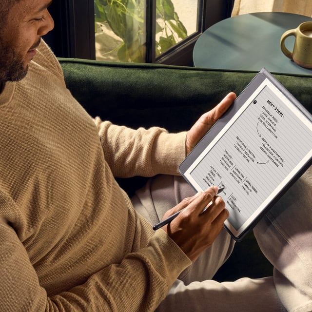 man sitting in chair and using Kindle Scribe to take notes