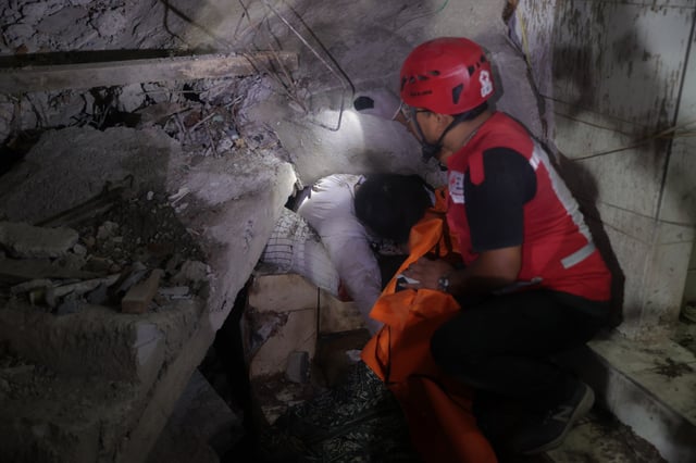 EDS NOTE: GRAPHIC CONTENT - A rescuer attempts to remove the trapped body of a victim after a building collapsed at an Islamic boarding school in Sidoarjo, East Java, Indonesia, Monday, Sept. 29, 2025. (AP Photo/Trisnadi)