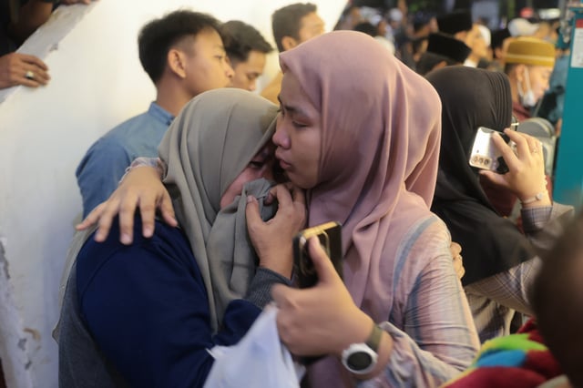 A woman is being comforted as she weeps while rescue work is underway after a building collapsed at an Islamic boarding school in Sidoarjo, East Java, Indonesia, Monday, Sept. 29, 2025. (AP Photo/Trisnadi)