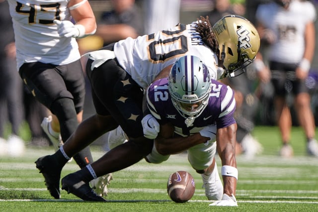 Kansas State wide receiver Jaron Tibbs (12) recovers his own fumble as he is tackled by Central Florida linebacker Lewis Carter (20) during the first half of an NCAA college football game Saturday, Sept. 27, 2025, in Manhattan, Kan. (AP Photo/Charlie Riedel)