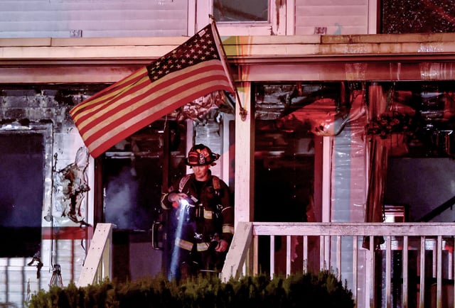 A firefighter at the charred entrance of the Gabriel House on Oliver Street in Fall River.
