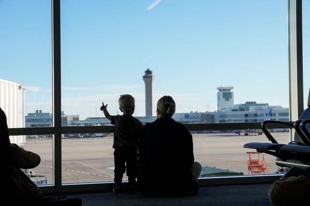 The air traffic control tower is seen from the gate as a woman and a child look out at the Denver International Airport terminal, in Denver, Colorado, U.S., May 15, 2025.  REUTERS/Megan Varner
