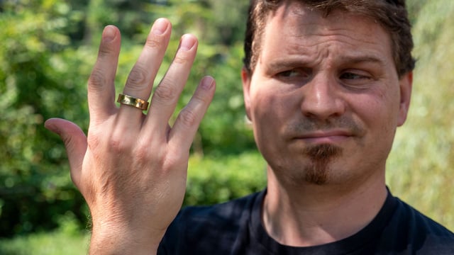 The looking at the gold Samsung Galaxy Ring with an expression of doubt