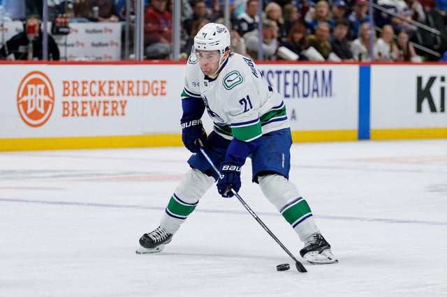 Apr 10, 2025; Denver, Colorado, USA; Vancouver Canucks left wing Nils Hoglander (21) controls the puck in the first period against the Colorado Avalanche at Ball Arena. Mandatory Credit: Isaiah J. Downing-Imagn Images