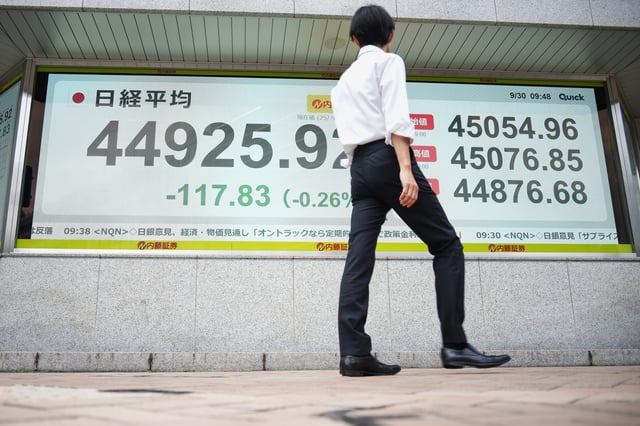 A man looks at an electronic stock board showing Japan's Nikkei 225 index at a securities firm Tuesday, Sept. 30, 2025, in Tokyo. (AP Photo/Eugene Hoshiko)