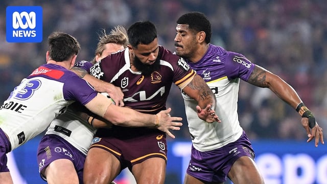 NRL player running with the ball, tackled by three defenders