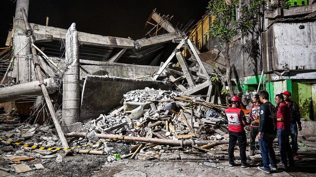 Rettungskräfte stehen vor einem eingestürzten Gebäude in Sidoarjo (Indonesien).