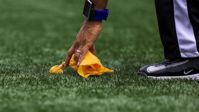 Sep 14, 2025; Cincinnati, Ohio, USA; Line judge Greg Bradley (98) picks up a penalty flag during the first half in the game between the Jacksonville Jaguars and the Cincinnati Bengals at Paycor Stadium. Mandatory Credit: Katie Stratman-Imagn Images