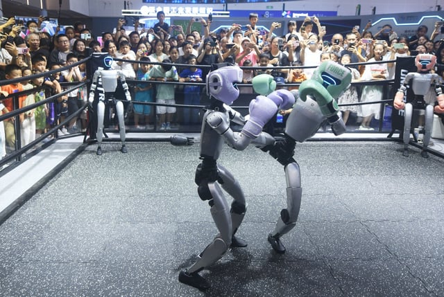 People watch two Unitree humanoids fighting in a boxing ring during a tech show in Hangzhou in east China's Zhejiang province on September 28, 2025.