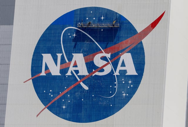Workers pressure wash the logo of NASA on the Vehicle Assembly Building before SpaceX will send two NASA astronauts to the International Space Station aboard its Falcon 9 rocket, at the Kennedy Space Center in Cape Canaveral, Florida, U.S., May 19, 2020. REUTERS/Joe Skipper/File Photo